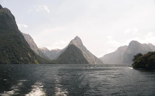 Milford Sound fiord in New Zealand with sunlit peaks reflected in still water