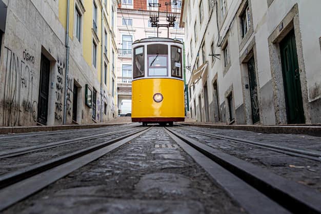 Yellow tram going down a narrow Lisbon alley surrounded by old tiled buildings
